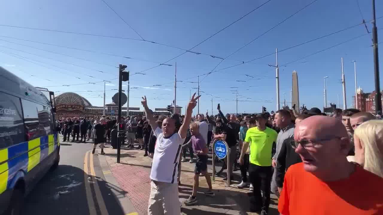 Cánticos de fútbol de los seguidores de Tommy Robinson en el mitin de Blackpool. Miembros de la multitud llaman a los policías varones nonces y difaman a las mujeres como malditas perras infértiles.