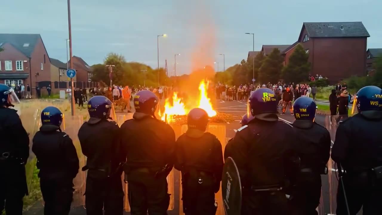 Los alborotadores están avivando otra hoguera en la carretera principal hacia el hotel para inmigrantes de Rotherham. Es Manvers Way, la A633, y está flanqueada por casas a ambos lados.